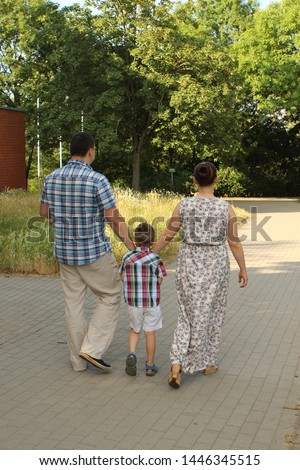 family walks along the path in the green summer the park, the concept of a happy family