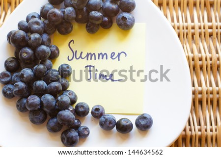 Fresh picked organic blueberries in a white plate on a woven basket slate background
