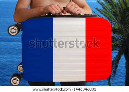 tourist holds with two hands a suitcase with the national flag of France, a symbol of vacation, immigration
