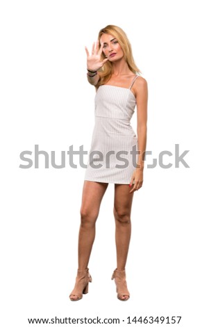 A full-length shot of a Young blonde woman making stop gesture over isolated white background