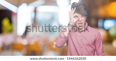 Young handsome business man over isolated background doing ok gesture with hand smiling, eye looking through fingers with happy face.