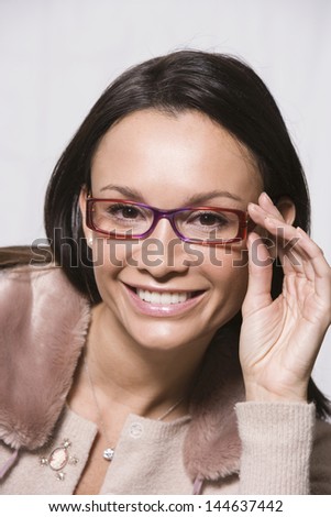Closeup portrait of a smiling woman looking through new glasses against gray background