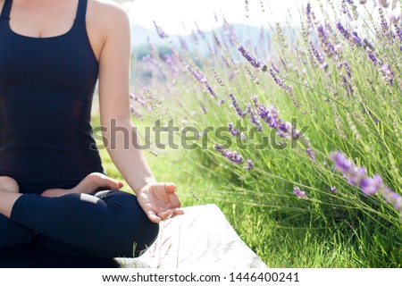Woman is practicing yoga in lavender field. Girl is meditating, sitting in lotus pose outdoors. Sport workout at nature. Concept of healthy lifestyle, wellbeing. Female fitness classes. Close up Royalty-Free Stock Photo #1446400241