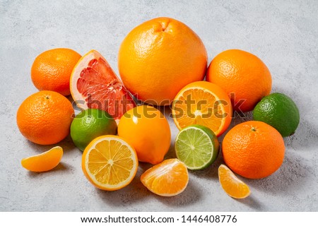 group of whole and sliced citrus fruits - tangerines, lemons, limes, oranges, grapefruits on the surface of the gray table - image