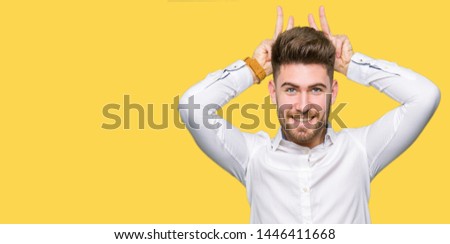 Young handsome business man Posing funny and crazy with fingers on head as bunny ears, smiling cheerful