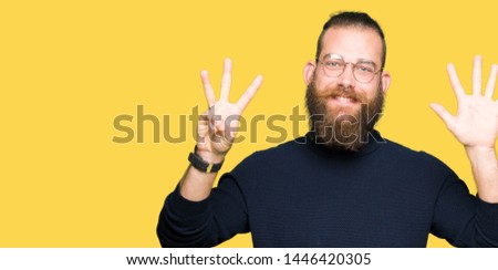 Young blond man wearing glasses and turtleneck sweater showing and pointing up with fingers number eight while smiling confident and happy.