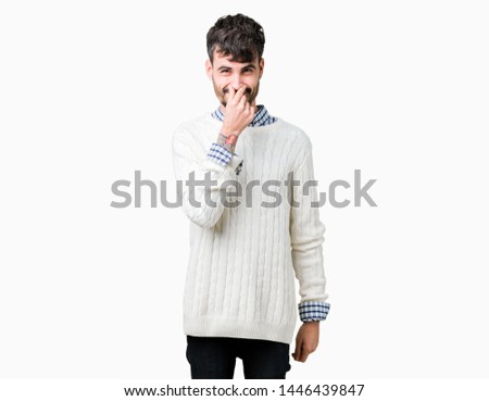 Young handsome man wearing winter sweater over isolated background smelling something stinky and disgusting, intolerable smell, holding breath with fingers on nose. Bad smells concept.
