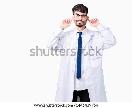 Young professional scientist man wearing white coat over isolated background Smiling pulling ears with fingers, funny gesture. Audition problem