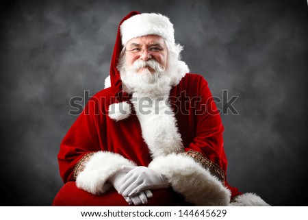 Santa Claus looking into the camera with traditional background and hands crossed in front of him