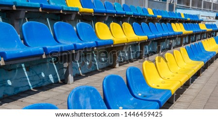 Old plastic chairs blue and yellow in the stadium or playground. Places for spectators of sports competitions