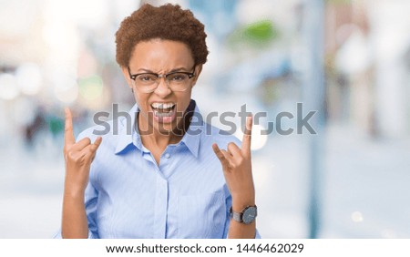 Young beautiful african american business woman over isolated background shouting with crazy expression doing rock symbol with hands up. Music star. Heavy concept.