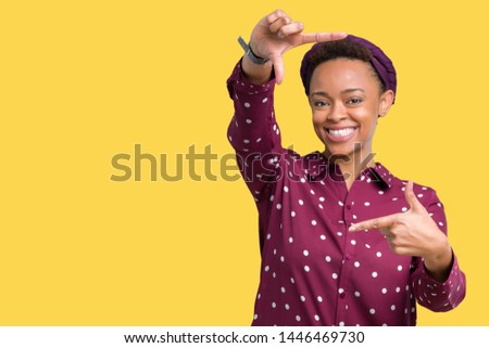 Beautiful young african american woman wearing head scarf over isolated background smiling making frame with hands and fingers with happy face. Creativity and photography concept.