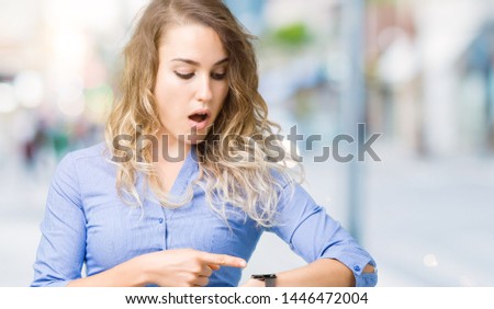Beautiful young blonde business woman over isolated background In hurry pointing to watch time, impatience, upset and angry for deadline delay