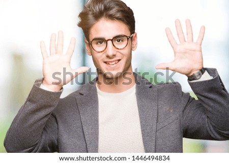 Young business man wearing glasses over isolated background showing and pointing up with fingers number ten while smiling confident and happy.