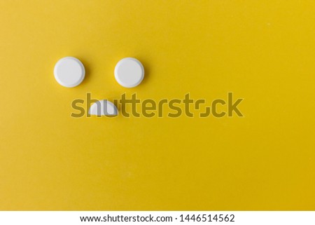 white round pills on a yellow background with copy space in the form of a smiley

