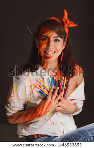 girl artist in a white shirt and a picture on the skin in the form of fire with colored pencils in her hand