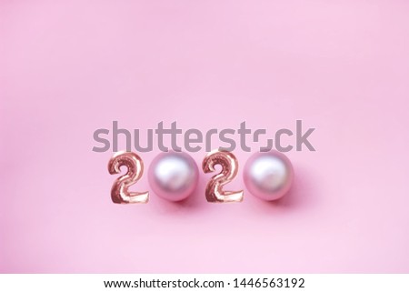 new year 2020. festive background, minimalism, space for text. top view. pink background, figures and pearl Christmas toys