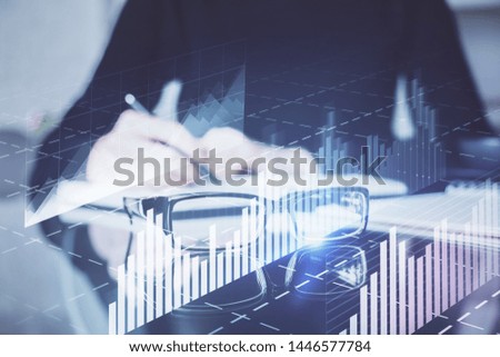 Forex chart hologram on hand taking notes background. Concept of analysis. Double exposure