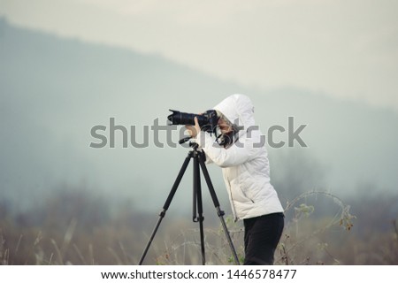 photographer with camera and tripod outdoor making landscape picture