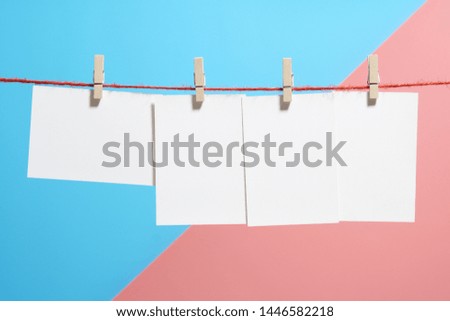 rows of empty photo frames hanging with clothespins on two tone pastel paper  background