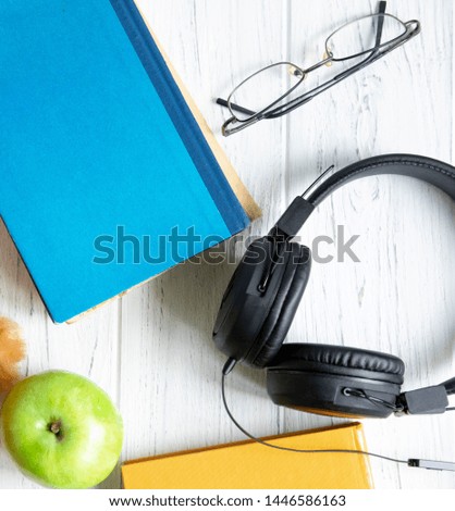 Photo with books, headphones and glasses on a wooden background with a place for copispeys. Frame for text banner on the subject of accounting, study and training. School and exams, tests