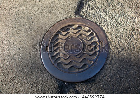 Sewer manhole on the urban asphalt road. Closeup photo