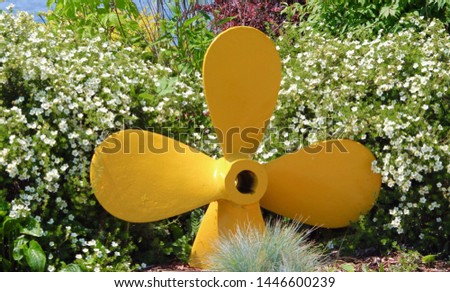 Boat propeller painted yellow in spring garden.  