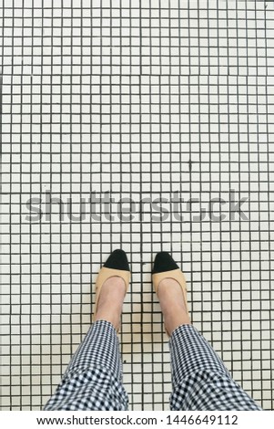 Selfie above view of Top View of Women's shoes on White Tile, Black and Tan Two Tone Pumps, Checkered Pants, Unique Tile Floor