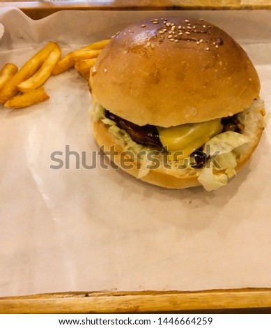 Picture of Cheese Burger with fries on background on wooden tray with copy space for text.