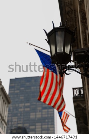 New York city street lamp. Typical architecture and design of the city. Black and white photography with blurred background and the American flag in colour