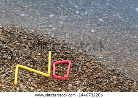 colorful plastic single use straw waste  washed up on the beach forming the word NO illustrating stop pollution
