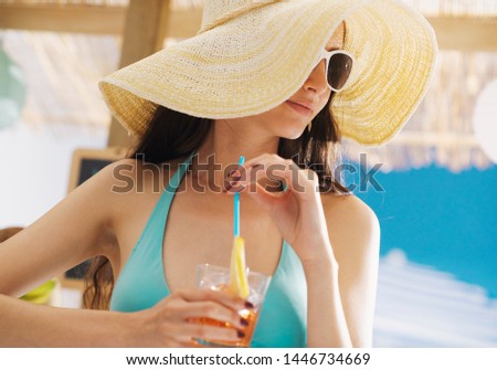 Beautiful girl at the beach, she is having a refreshing cocktail and drinking with a straw