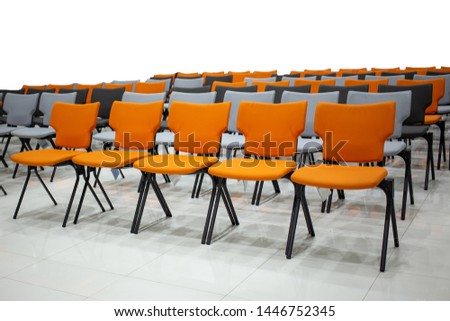 The orange, gray and black chairs are neatly arranged with  white background.