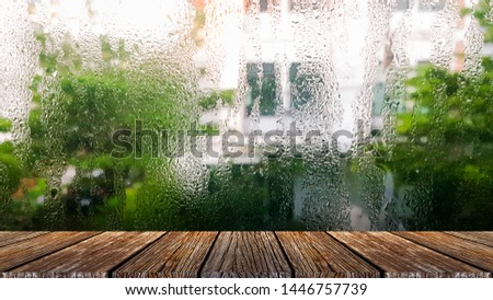 The small raindrops on the window glass in the rainy season intersect with the green backdrop. plank table surface. Free place for creativity. Background.