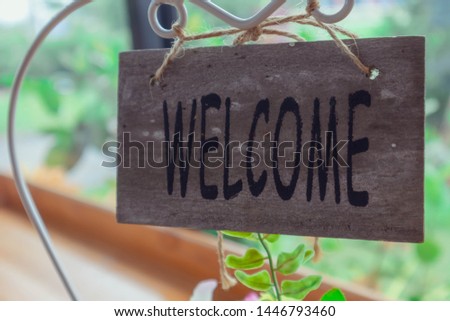 Close up of wooden retro welcome sign with surface texture. Background of blur green natural park. Abstract backdrop and wallpaper. Copy space for text and frame photo concept. Selective focus.