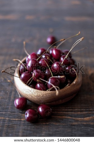 Dark red cherries in a bowl on wooden and gray  background 
