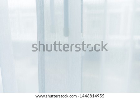 White blinds luxury cloth for luxurious elegant wallpaper design. Close up of White curtains and large glass window with sunlight in the morning. Silk curtain wavy folds of grunge silk texture satin