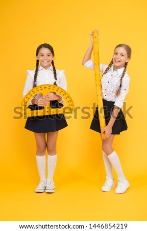 happy math. stem disciplines. back to school. Maths and geometry. Kids in uniform at yellow wall. friendship and sisterhood. happy small girls study mathematics. students use protractor ruler.