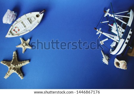 Two little toy ships and shells on a blue background. Top view. Copy space