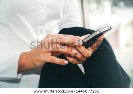 Close up hand businesswoman use modern touch screen mobile phones as part of everyday life while standing in the office.



