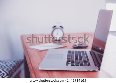 Comfortable working place in home office with wooden table and modern laptop laying on it. Freelance work concept with natural light. Work from home during quarantine isolation