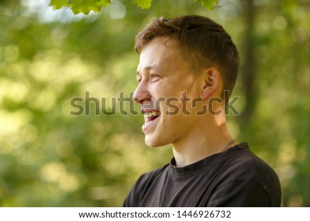 a guy in a black t-shirt on a tree background,shot on a summer day