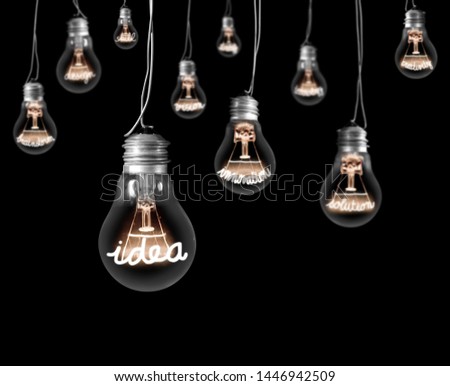 Group of hanging light bulbs with shining fiber in a shape of Idea and Innovation concept isolated on black background