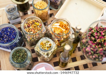 group of glass jars with dried herbs for aromatherapy on wooden 