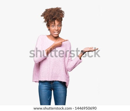 Beautiful young african american woman wearing glasses over isolated background amazed and smiling to the camera while presenting with hand and pointing with finger.