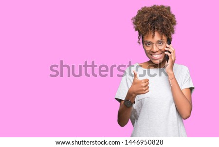 Young african american woman talking on smartphone over isolated background happy with big smile doing ok sign, thumb up with fingers, excellent sign
