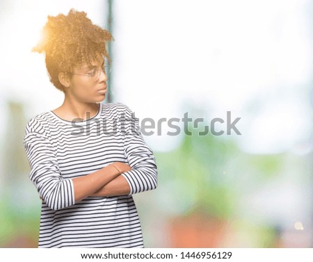 Beautiful young african american woman wearing glasses over isolated background smiling looking to the side with arms crossed convinced and confident
