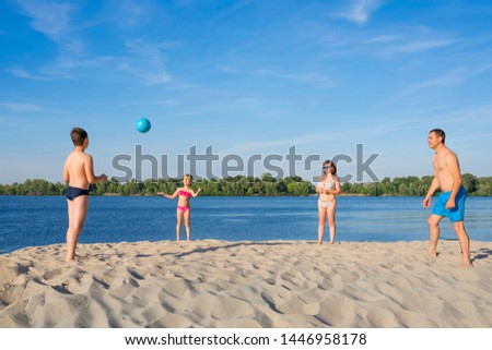 A family on the river bank playing with a ball.  Summer season.  Sports lifestyle.