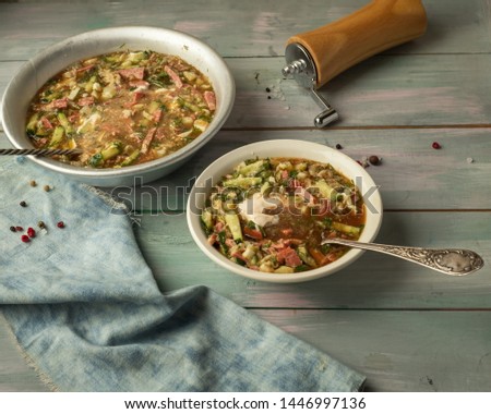 Cool light soup on kvass with fresh vegetables on a wooden tray, denim napkin and wooden pepper shaker-mill. Serving on a wooden tray
