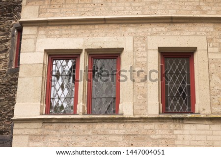Three red windows in a stone facade (Germany, Europe)